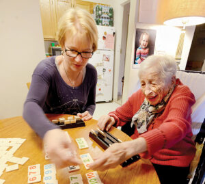 woman assists her mother with rummikub game while discussing care from compassus