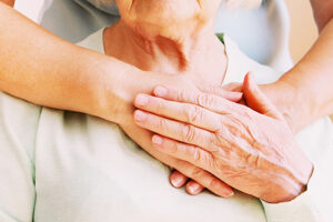loved one places hands on patient's heart while considering the signs it may be time for hospice care