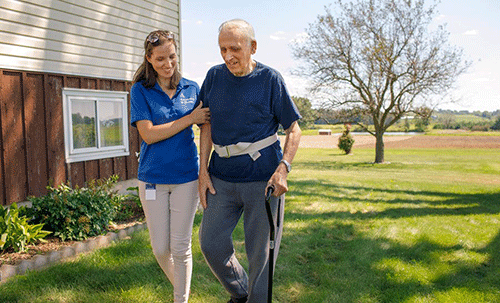 a nurse walks with an elderly man patient outside providing him with home health care