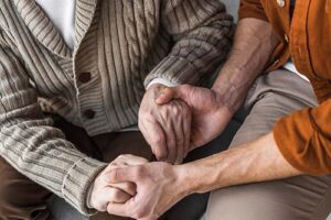 shot of patient and loved one holding hands while discussing hospice care for late stage huntington's disease