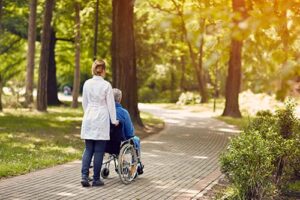 nurse wheels patient while discussing hospice criteria for amyotrophic lateral sclerosis