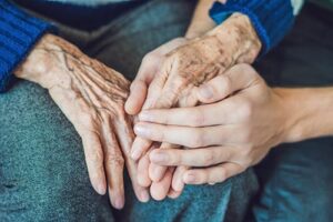 shot of clasped hands as patient and loved one discuss eligibility criteria for stroke or cva