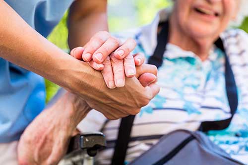 patient and nurse clasp hands while discussing hospice home care supplies