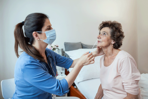 nurse swabs inside of patient nose while discussing hospice and coronavirus faqs