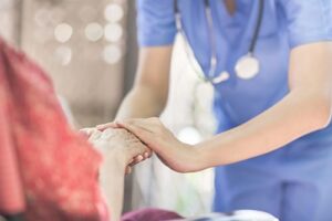 nurse clasps hands with patient while discussing hospice and palliative care for late stage copd