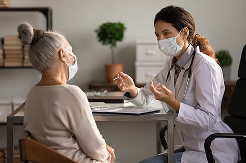 doctor explains to patient how to keep hospice patients and caregivers healthy during the covid 19 pandemic