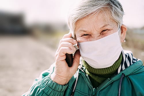 woman with mask talks on phone about maintaining meaningful connections during the coronavirus pandemic