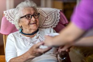 patient smiles as nurse reaches out for their hands and discusses palliative care vs hospice care