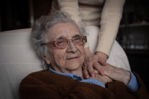 woman looks at camera with loved one's hand on shoulder discussing signs that your loved one needs hospice care