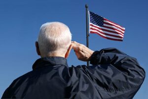 man salutes the flag while considering the we honor veterans program