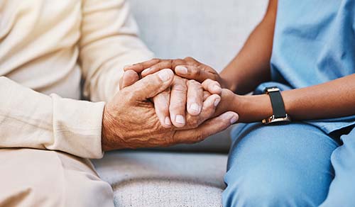 patient and nurse clasp hands while discussing examples of end of life conversations