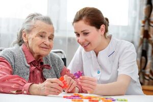 nurse assists hospice patient with craft and discusses hospice criteria for dementia