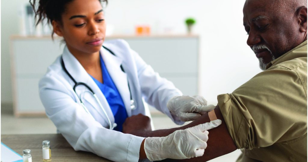 Female nurse placing band aid on male after vaccine