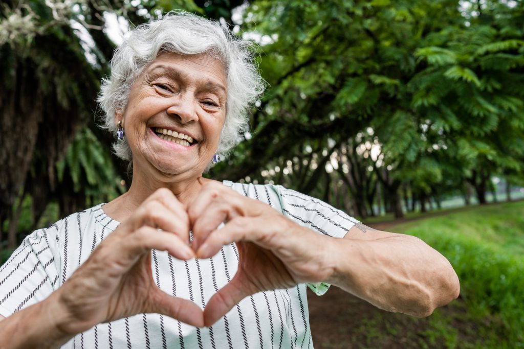 A senior woman making a heart symbol with her hands