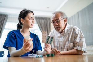 Female nurse discusses medications with older adult male patient